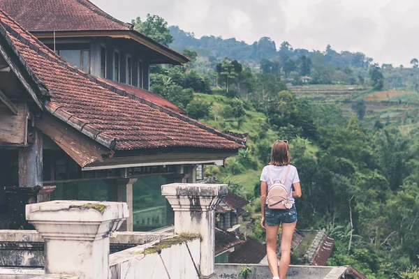 Beautiful young woman with backpack on tropical jungle background. Bali island, Indonesia. Asia.