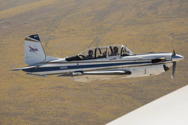NASA Aircraft flies over yellow wildflowers abundant due to rainy winter season. The T-34 aircraft was flown from the agency's Armstrong Flight Research Center.