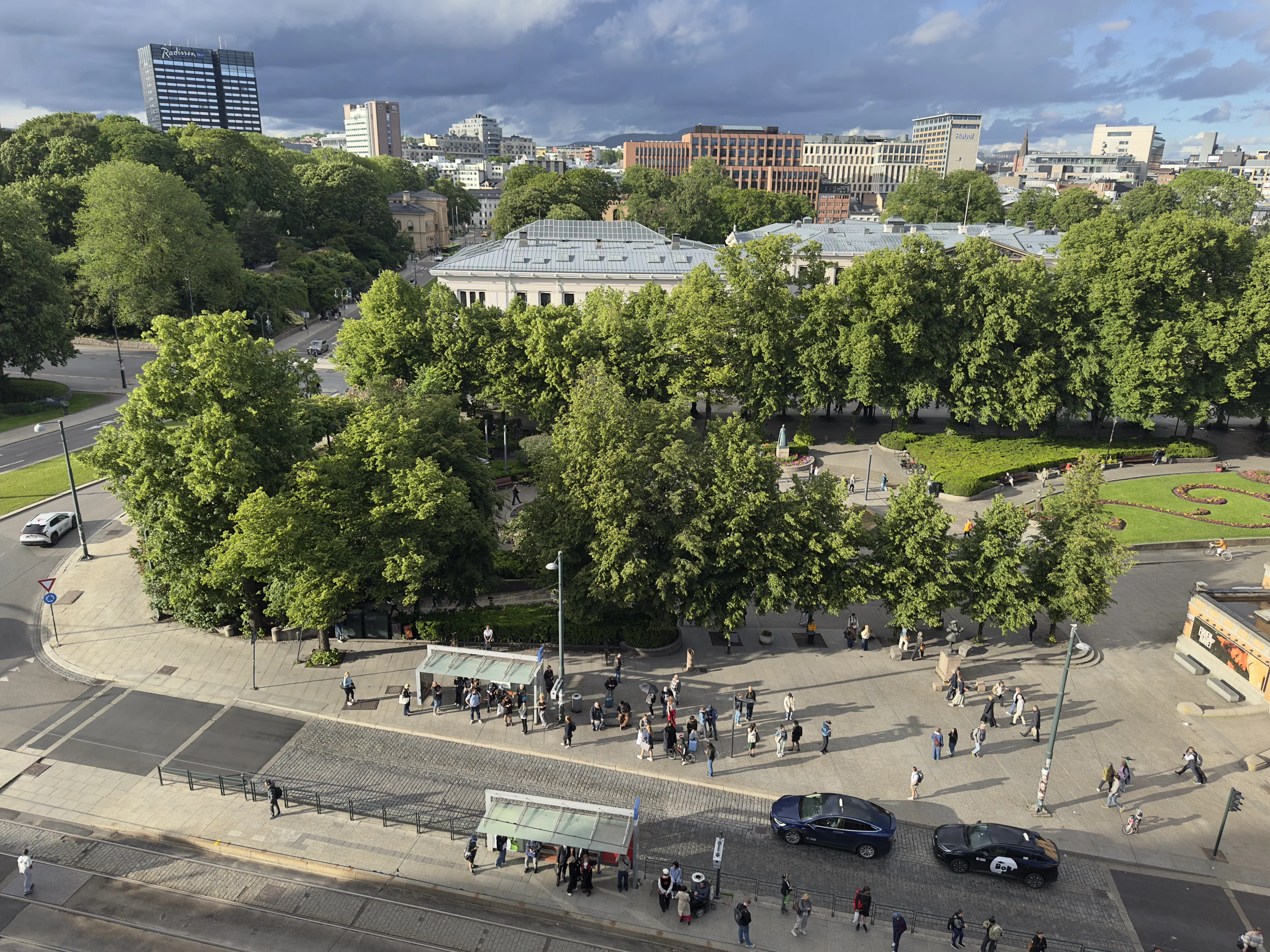 OSLO Norway 2026-06-10 Overlooking rooftop cityscape view towards north from Odd Fellow-bygn. (Stortingsg 28) Slottsparken Frederiks gate NATIONALTHEATRET holdeplass bus stop JOHANNE DYBWADS PL. Studenterlunden Universitetet pedestrian