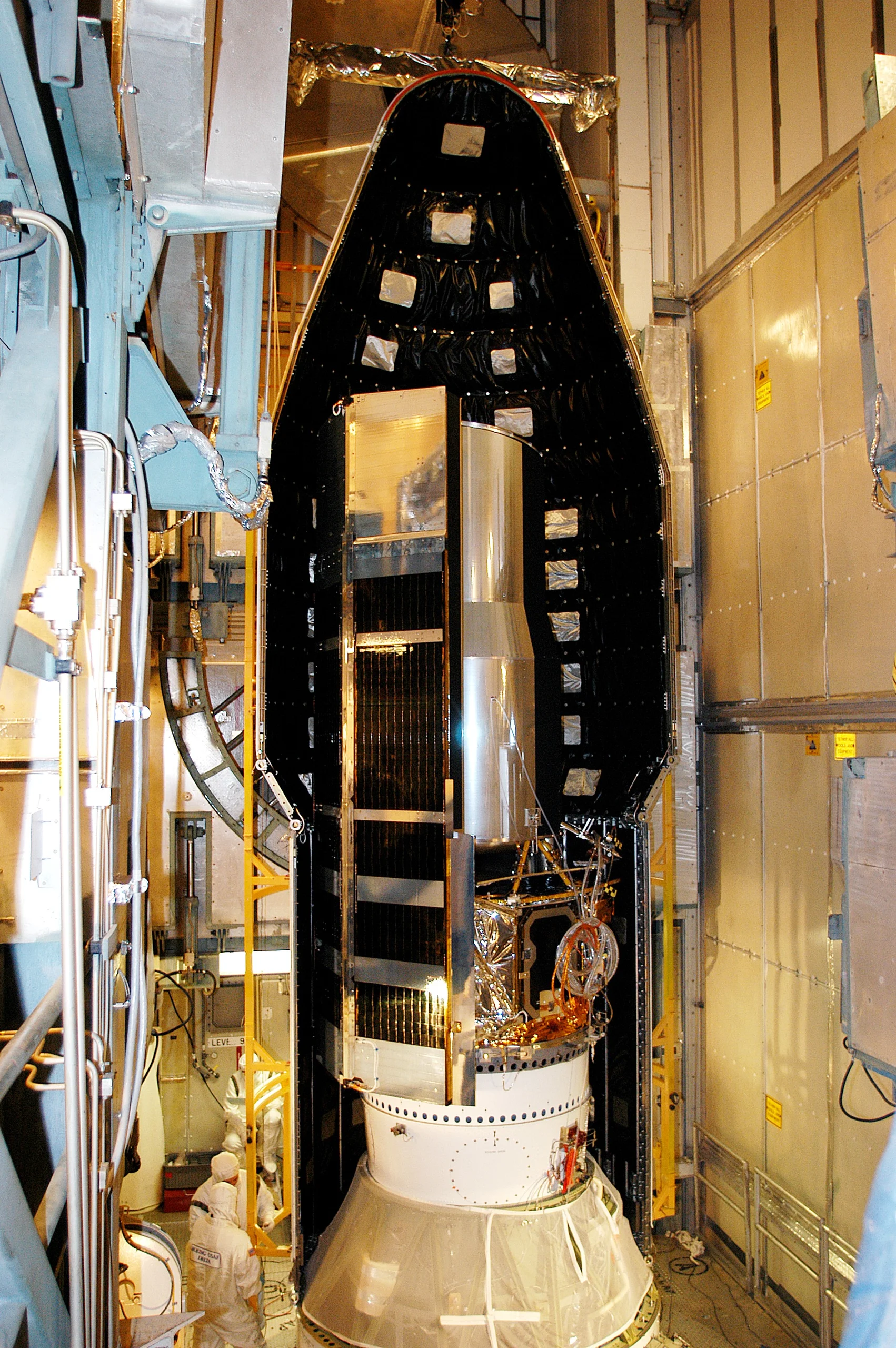 KENNEDY SPACE CENTER, FLA.  - In the mobile service tower on Launch Pad 17-B, Cape Canaveral Air Force Station, the first half of the fairing is moved around the Space Infrared Telescope Facility (SIRTF). SIRTF will obtain images and spectra by detecting the infrared energy, or heat, radiated by objects in space. Consisting of a 0.85-meter telescope and three cryogenically cooled science instruments, SIRTF will be the largest infrared telescope ever launched into space. It is the fourth and final element in NASA’s family of orbiting “Great Observatories.” Its highly sensitive instruments will give a unique view of the Universe and peer into regions of space that are hidden from optical telescopes.