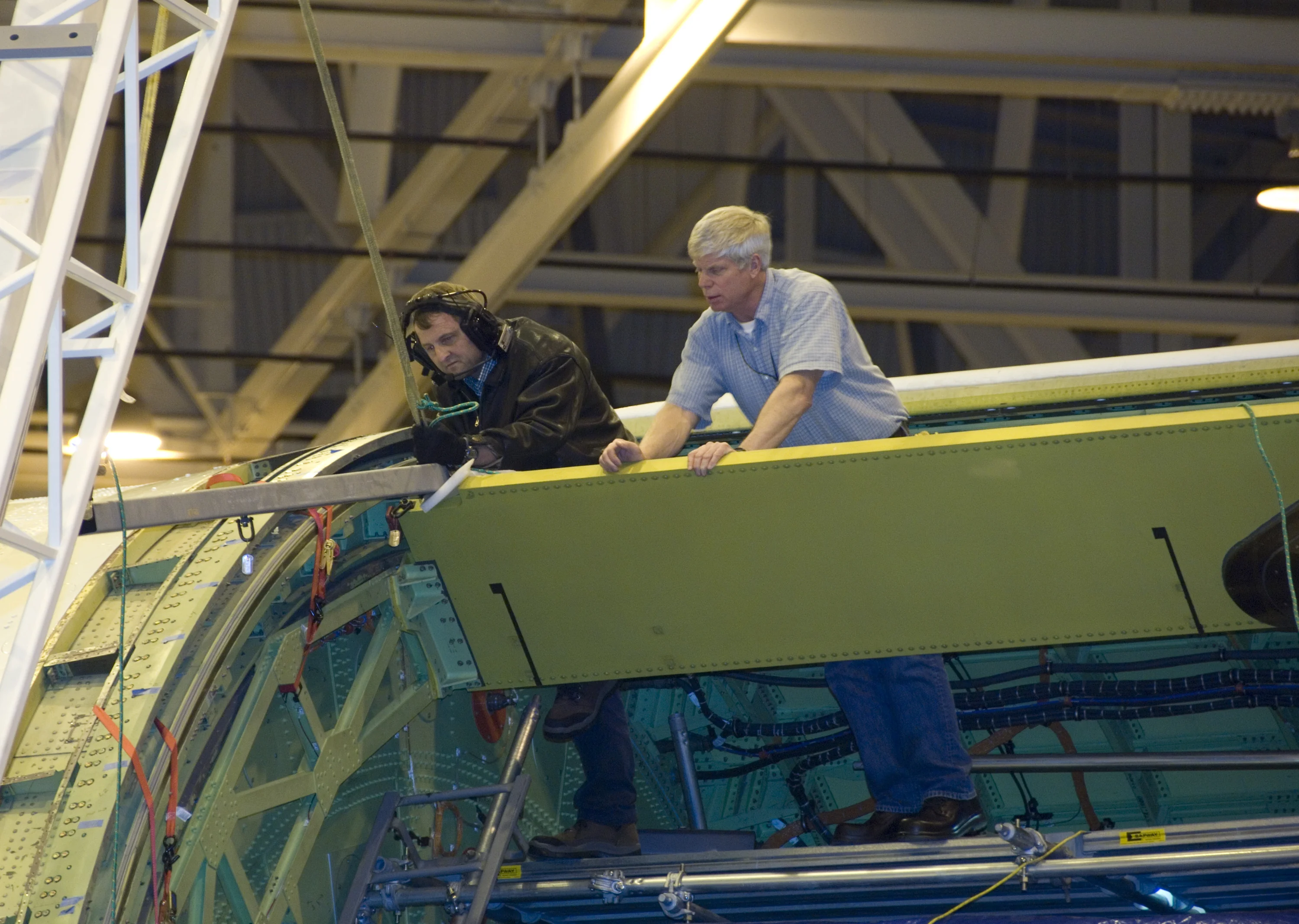 Technicians carefully maneuver a spreader bar into place before removing the telescope aperture assembly from NASA's SOFIA infrared observatory Boeing 747SP
